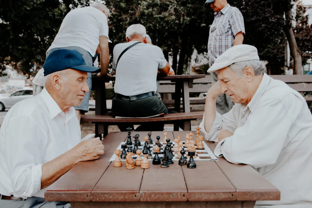 Two senior men playing chess outdoors