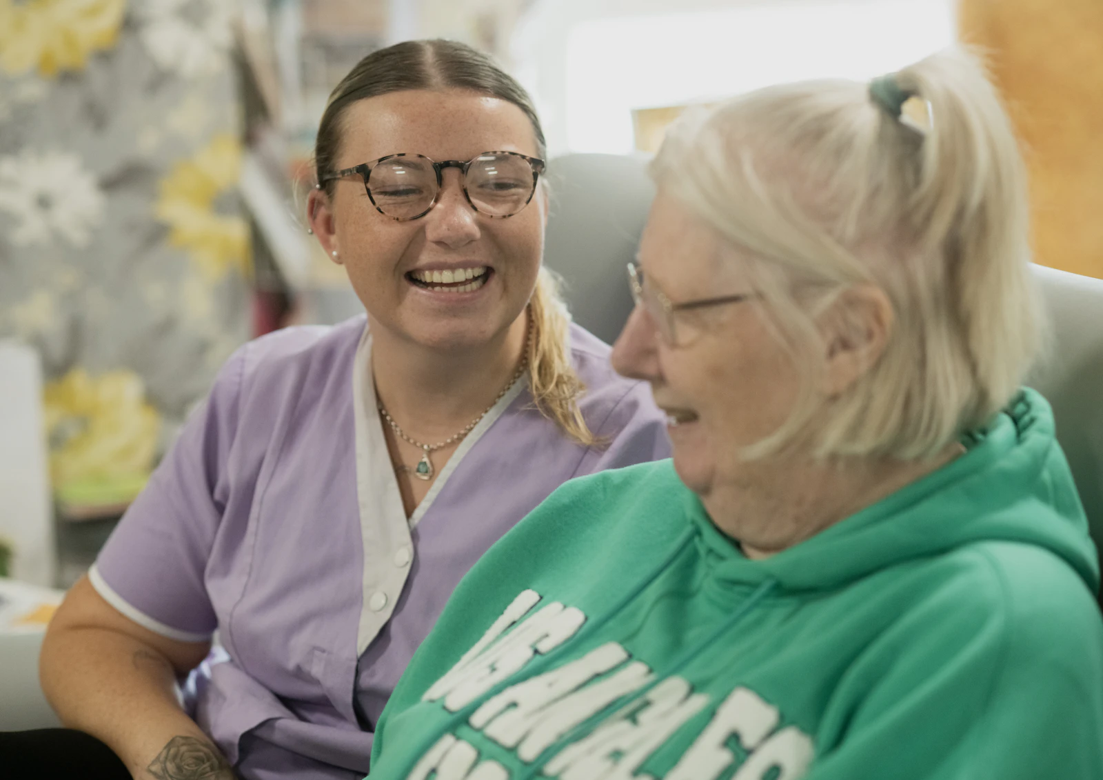 Caregiver and senior resident laughing together