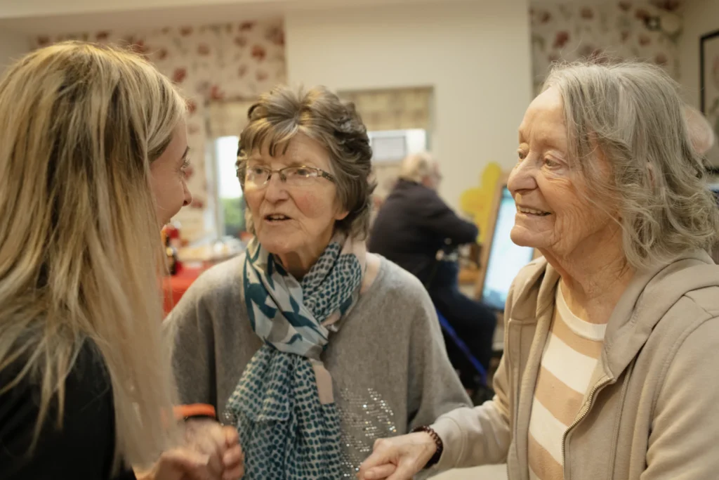 Caregiver chatting with two senior residents
