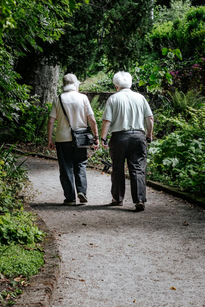 Senior couple walking along a shaded garden path