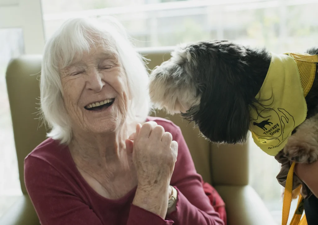Senior woman laughing with a visiting dog