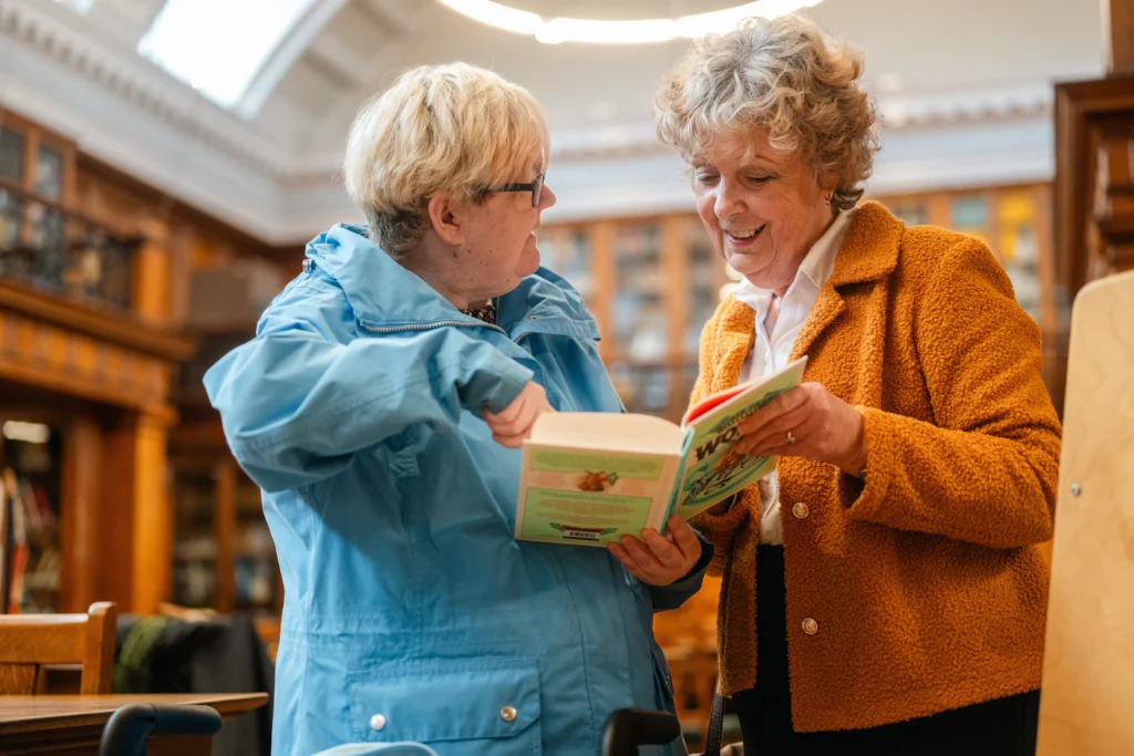 Two senior women sharing a book